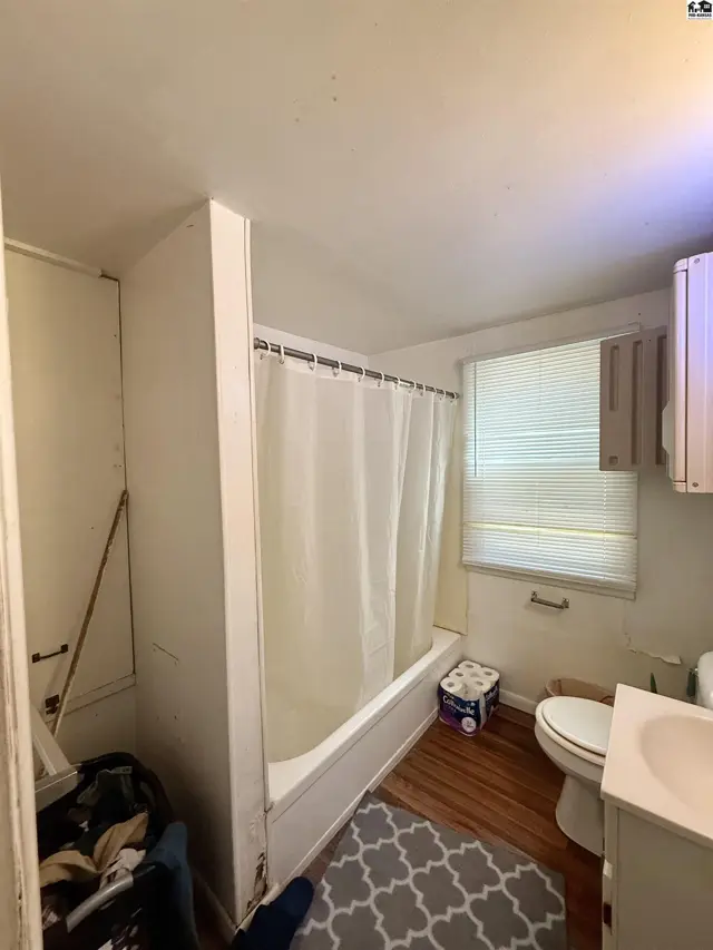 This bathroom features a bathtub with a shower curtain, toilet, and sink.