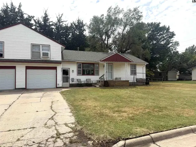 White siding house with attached garage and a large green lawn.