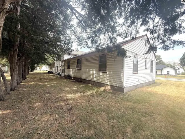 White clapboard siding covers this home with mature trees lining the grassy yard.