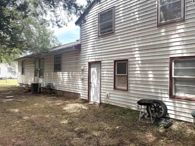 Exterior siding and windows of a two-story house with a side door.