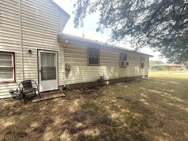 Exterior features include vinyl siding, a glass-paneled door, and a grassy yard.