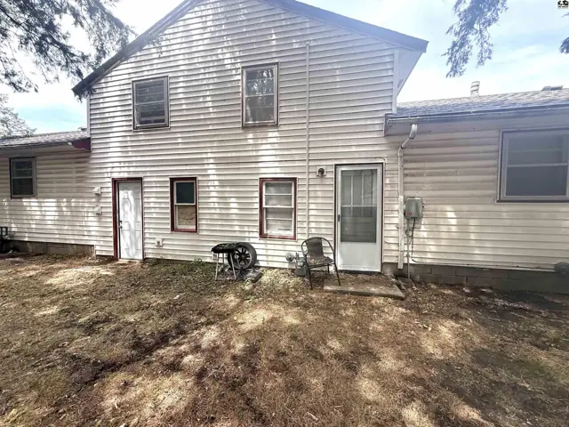Exterior siding and multiple doors are visible on this two-story structure with a grassy yard.