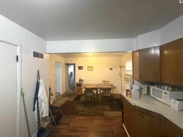 This interior view shows a kitchen area with wooden cabinets and a dining area with a table.