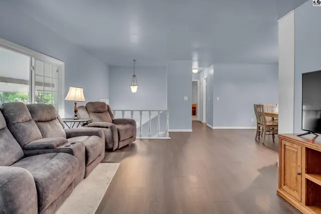 Spacious living area with plush seating, dark wood flooring, and a dining nook.