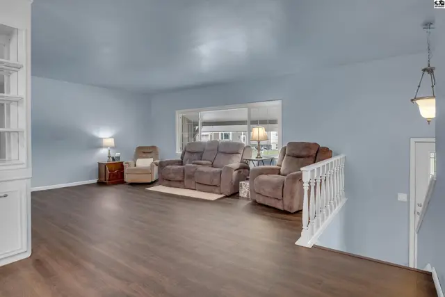 Spacious living area with plush seating and a large window overlooking a sunroom.