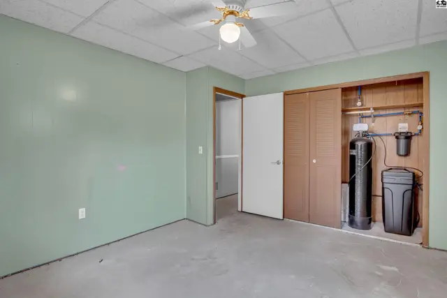 This room features light green walls, a concrete floor, and a ceiling fan.