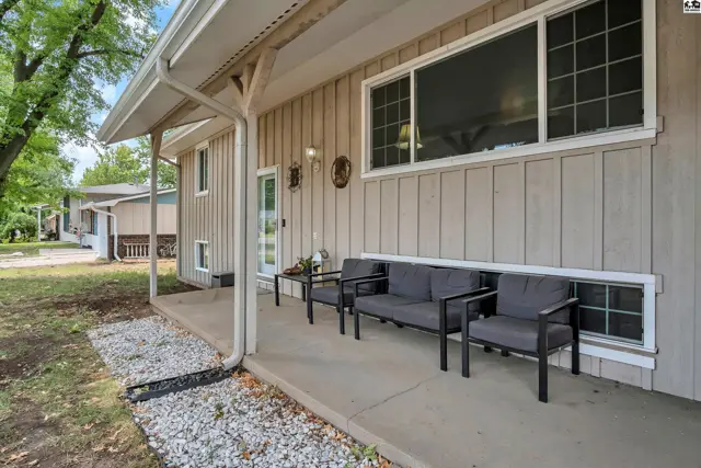 Covered porch with seating area and vertical wood siding.