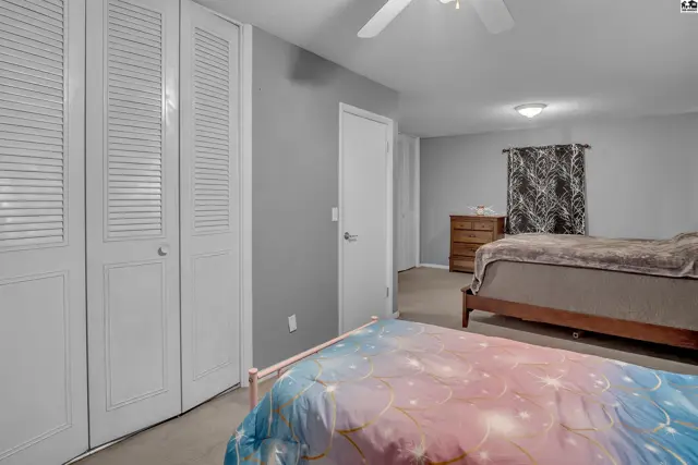 Spacious room with two beds, a dresser, and large white louvered closet doors.
