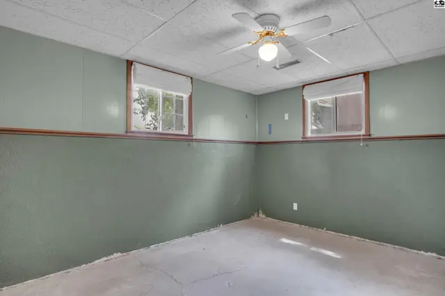 This room features painted walls, a wood-paneled accent, and a ceiling fan.