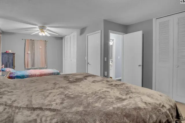 Spacious room with two beds, ceiling fan, and ample closet space.