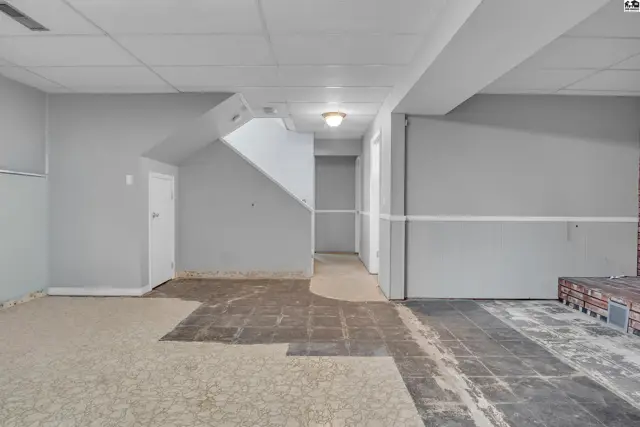 Unfinished basement with carpet and tile flooring, and a staircase.