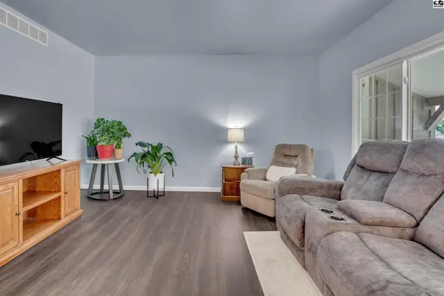 Living room features a television, recliner, and sofa with wood-look flooring.