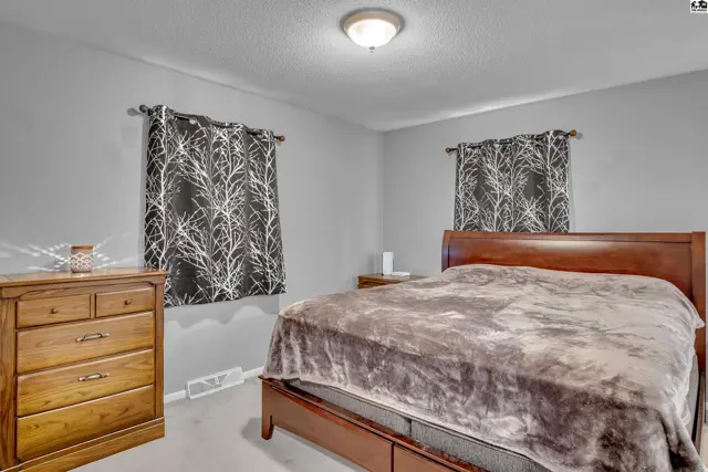 This bedroom features a wooden bed frame, dresser, and grey walls.