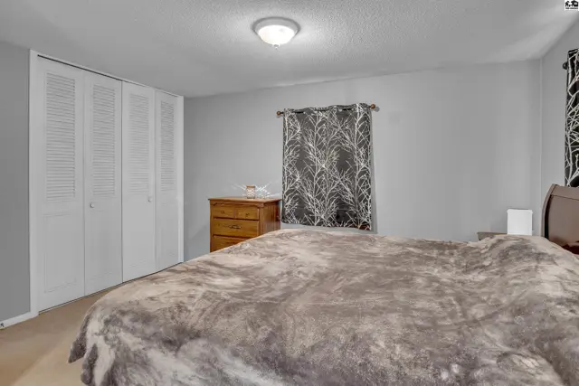 This bedroom features a large closet with bi-fold doors and a window with patterned curtains.