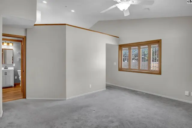Spacious room with carpet, ceiling fan, and a large window.