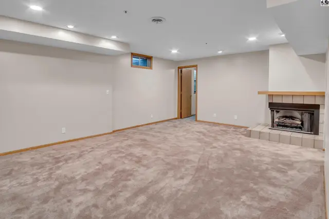 Spacious finished basement features a tiled fireplace and plush carpeting.