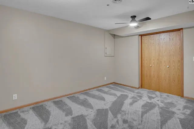 This room features neutral walls, a ceiling fan, and a large closet with wood-grain doors.
