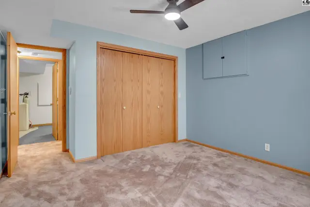 This room features a ceiling fan, light blue walls, and a large wooden closet.