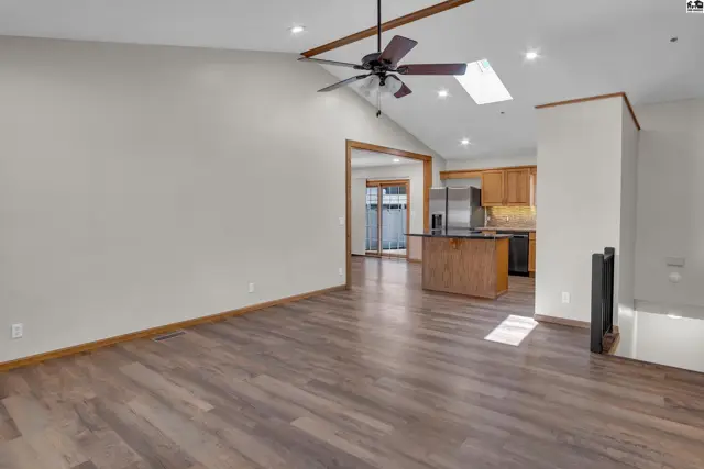 Vaulted ceiling living room with wood beams, skylight, and adjacent kitchen.
