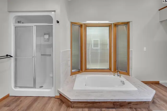 Spacious bathroom features a soaking tub and a separate glass-enclosed shower.