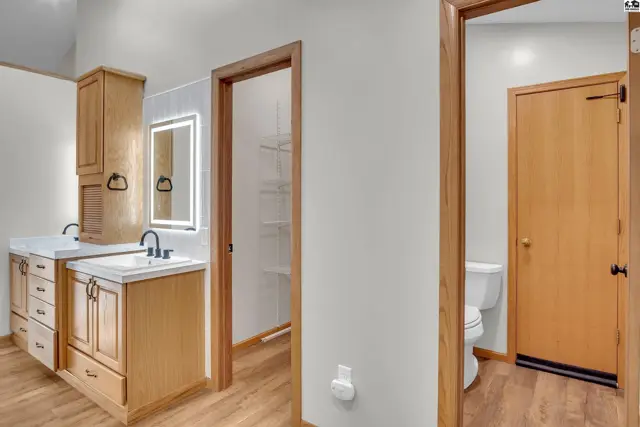This bathroom features a double vanity, a lighted mirror, and a separate toilet room.