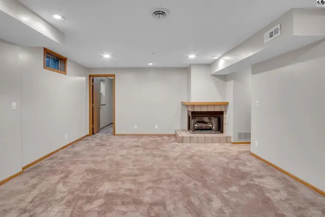 Spacious finished basement features a brick fireplace and neutral carpeting.