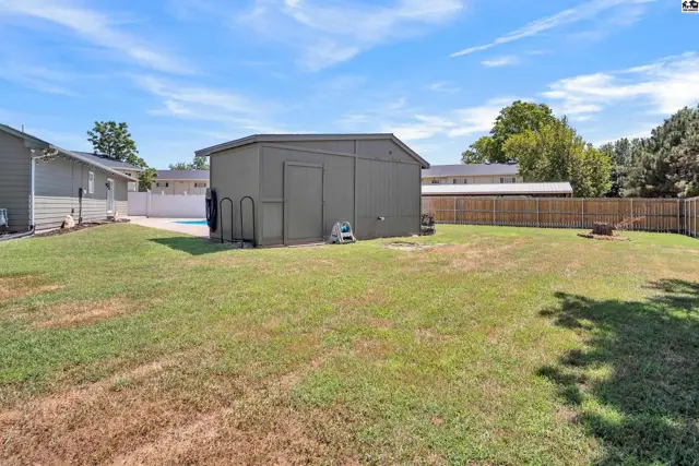 A large, fenced backyard features a detached storage shed and a swimming pool.
