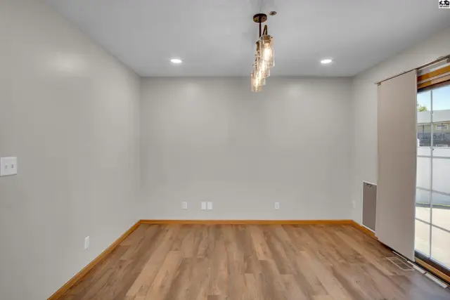 This room features light gray walls, wood-look flooring, and a modern chandelier.