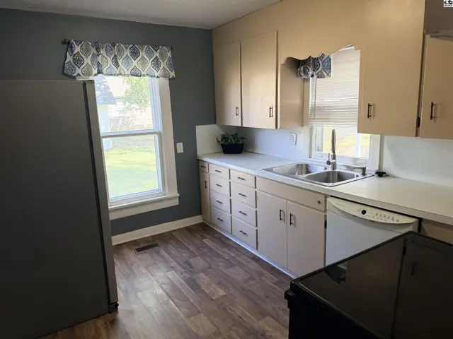 Kitchen features light wood cabinets, a double sink, and a dishwasher.