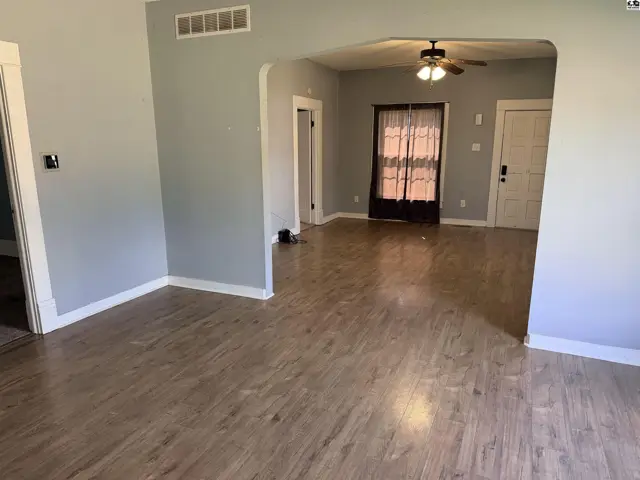 Light-filled living area with wood-look flooring and a ceiling fan.