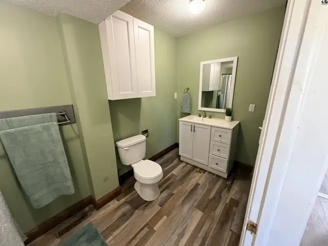 This bathroom features a white vanity, toilet, and a white cabinet above the toilet.