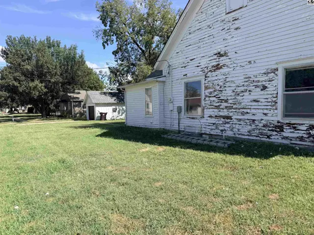White clapboard siding with peeling paint covers this home with a detached garage.