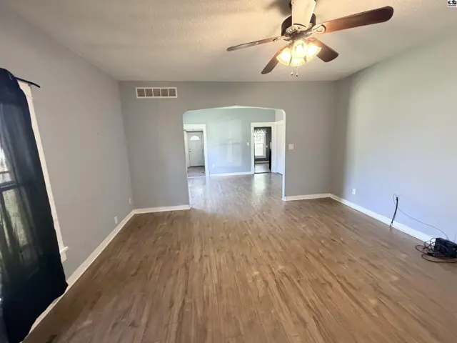 Spacious living area with wood-look flooring and a ceiling fan.