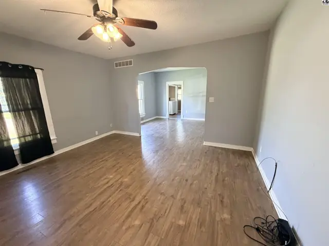 This living room features light grey walls, wood-look flooring, and a ceiling fan.