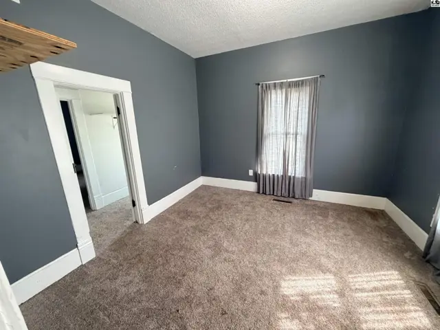 This room features grey walls, white trim, and a large window with sheer curtains.