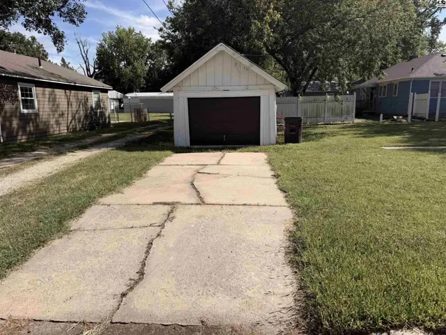 Concrete driveway leads to a detached garage with a dark-colored door.