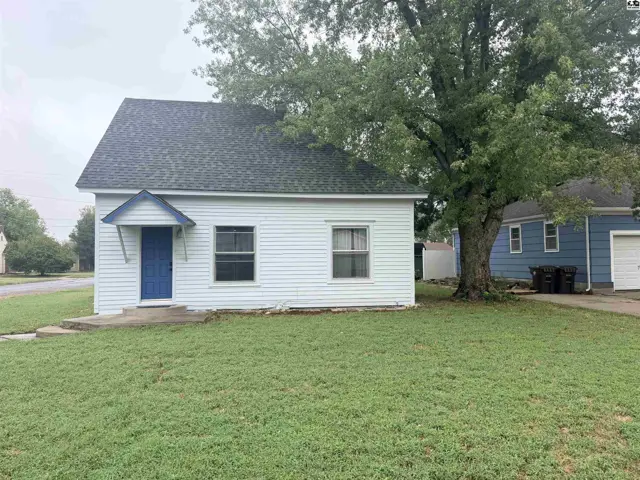 White vinyl-sided house with a blue door and asphalt shingle roof.