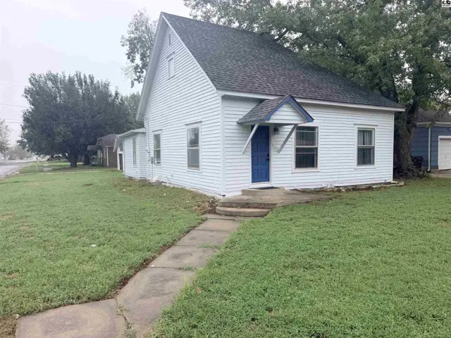White vinyl-sided house with a blue door and a concrete walkway.