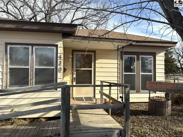 Exterior features a ramp, beige siding, and a brick planter.