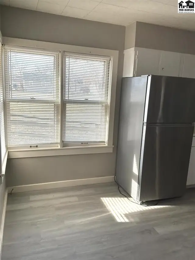 This kitchen features a stainless steel refrigerator and light-colored laminate flooring.