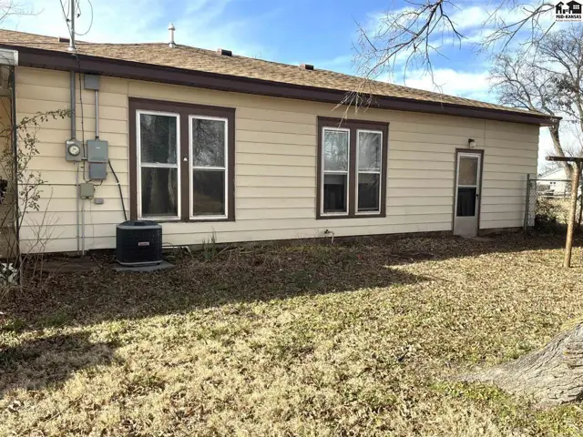 Exterior features tan siding, brown trim, and a small door with a screen.