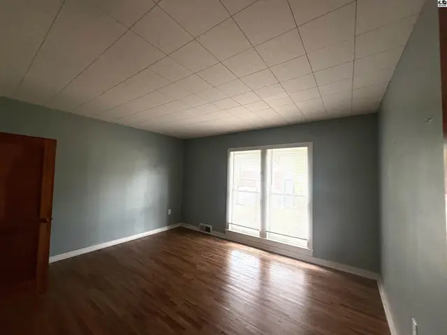 This room features hardwood floors, light blue walls, and a large window.