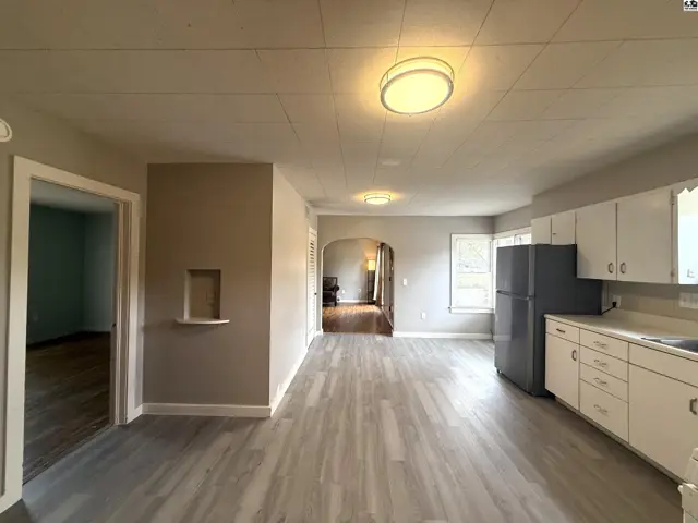 Open-concept living area with a kitchen featuring white cabinetry and a gray refrigerator.