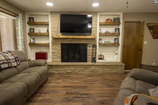 Living room features a stone fireplace, built-in shelving, and wood flooring.