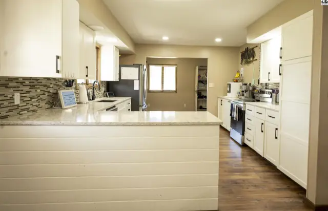 Spacious kitchen features white cabinetry, granite countertops, and wood-look flooring.