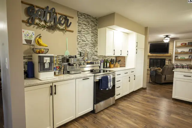 This kitchen features white cabinetry, granite countertops, and a stainless steel range.