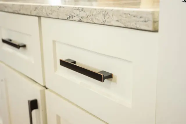 White shaker cabinets with dark bronze hardware and a granite countertop.
