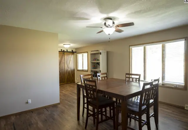 This dining area features a wood table, chairs, and a ceiling fan.