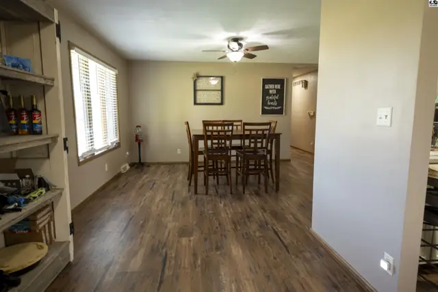 Wood-look flooring extends through this dining area with a ceiling fan and a table.