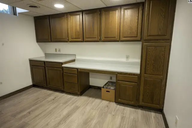 This room features a long, built-in desk with ample wood cabinetry and laminate countertops.